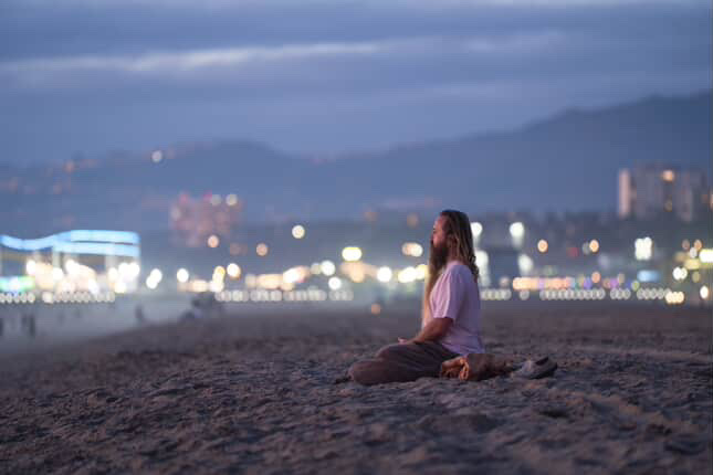Adam Wes meditating on the beach at dusk